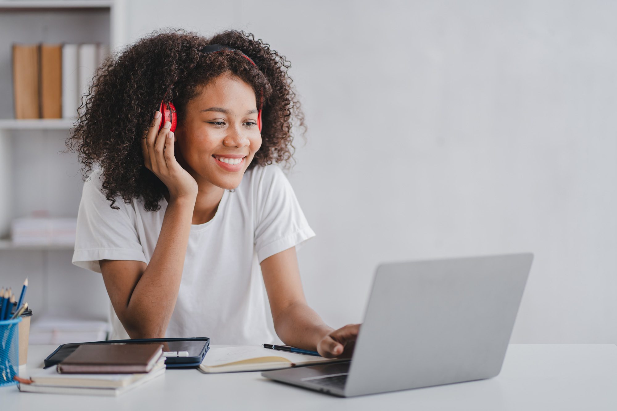 smiling woman wearing headphones and looking at a computer. university Dubuque online